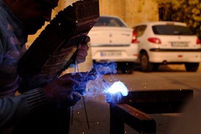 person doing welding on metal bar