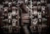 Complex machinery parts with heavy rust and wear, featuring interlocking gears and metal components. The image captures intricate details of industrial equipment showcasing bolts, nuts, and mechanical textures.