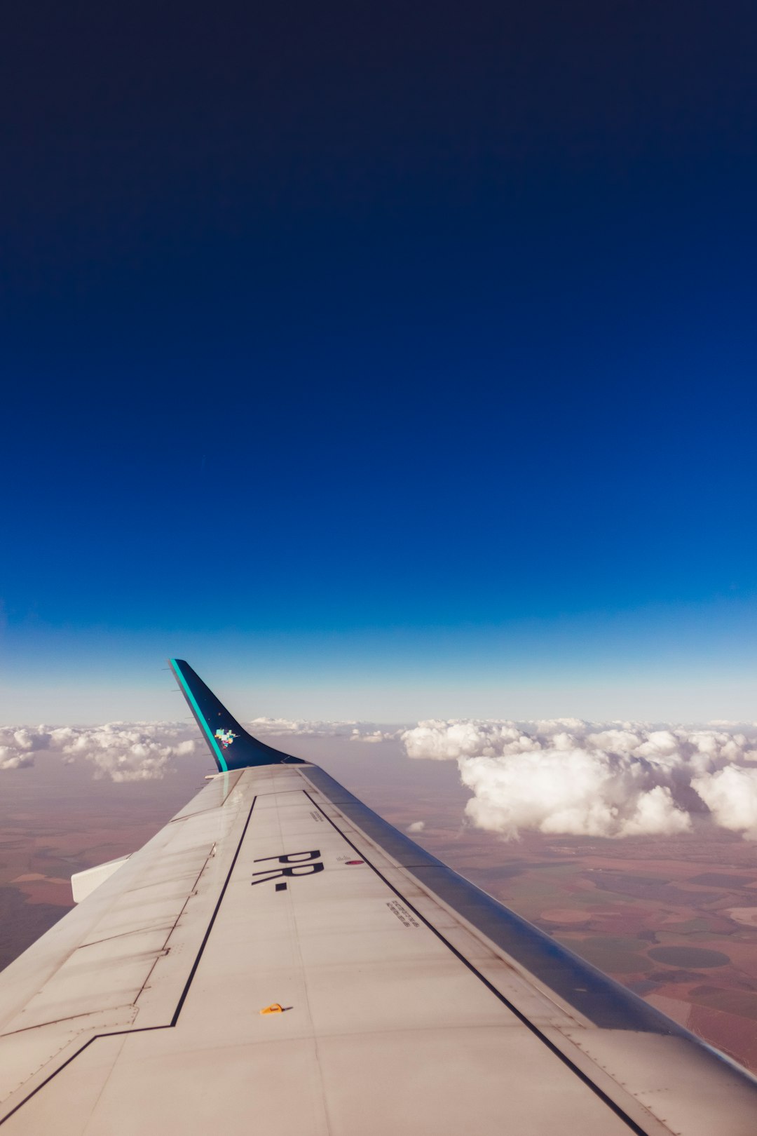 white and green plane wings above clouds