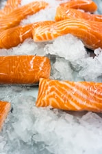 Close-up of fresh salmon fillets on ice, highlighting quality.