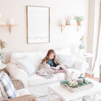 girl seated on sofa reading book