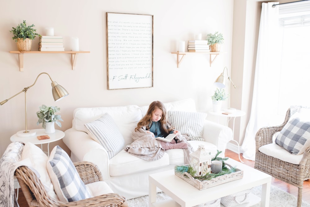 girl seated on sofa reading book