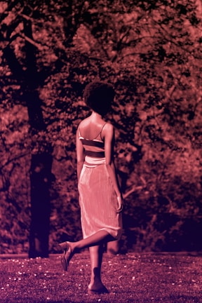 A model walking through a quiet park wearing muted blue and earthy tones.
