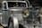 A vintage luxury car with a silver finish, featuring a prominent front grille and large round headlights. The vehicle showcases a classic, elegant design with intricate detailing.