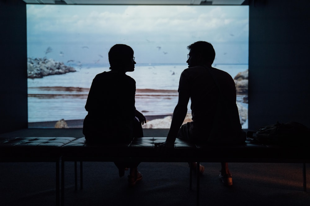 silhouette of man and woman sitting on ottoman