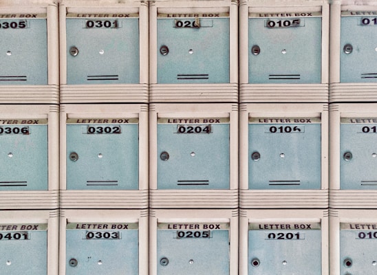 A grid of pale blue letterboxes are aligned in a neat, symmetrical pattern. Each box has a distinct number, ranging from 0201 to 0306, and a slot for mail. The letterboxes are housed in frames with a beige or off-white color.