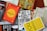 A collection of books is arranged haphazardly on a flat surface. The books are of various colors and titles, including 'The Alchemist,' 'The Best Places for Everything,' and 'You Are a Badass.' Some books are stacked on top of others, showing a mix of orientations with some covers facing up and others showing their spines.