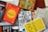 A collection of books is arranged haphazardly on a flat surface. The books are of various colors and titles, including 'The Alchemist,' 'The Best Places for Everything,' and 'You Are a Badass.' Some books are stacked on top of others, showing a mix of orientations with some covers facing up and others showing their spines.