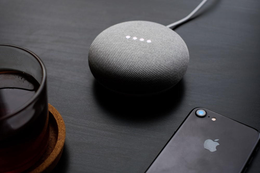 turned-on round gray Google Bluetooth speaker