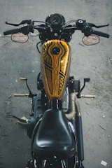 Close-up of a sleek custom airbrushed motorcycle tank with intricate golden patterns.