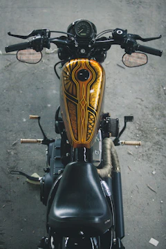Close-up of a sleek custom airbrushed motorcycle tank with intricate golden patterns.