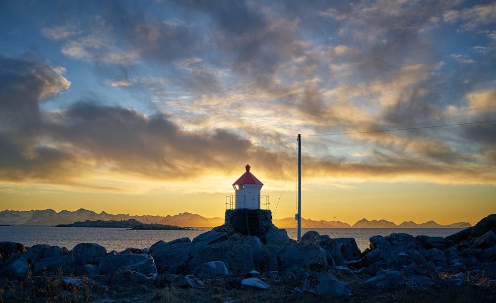 white and red lighthouse front of sea during golden hour