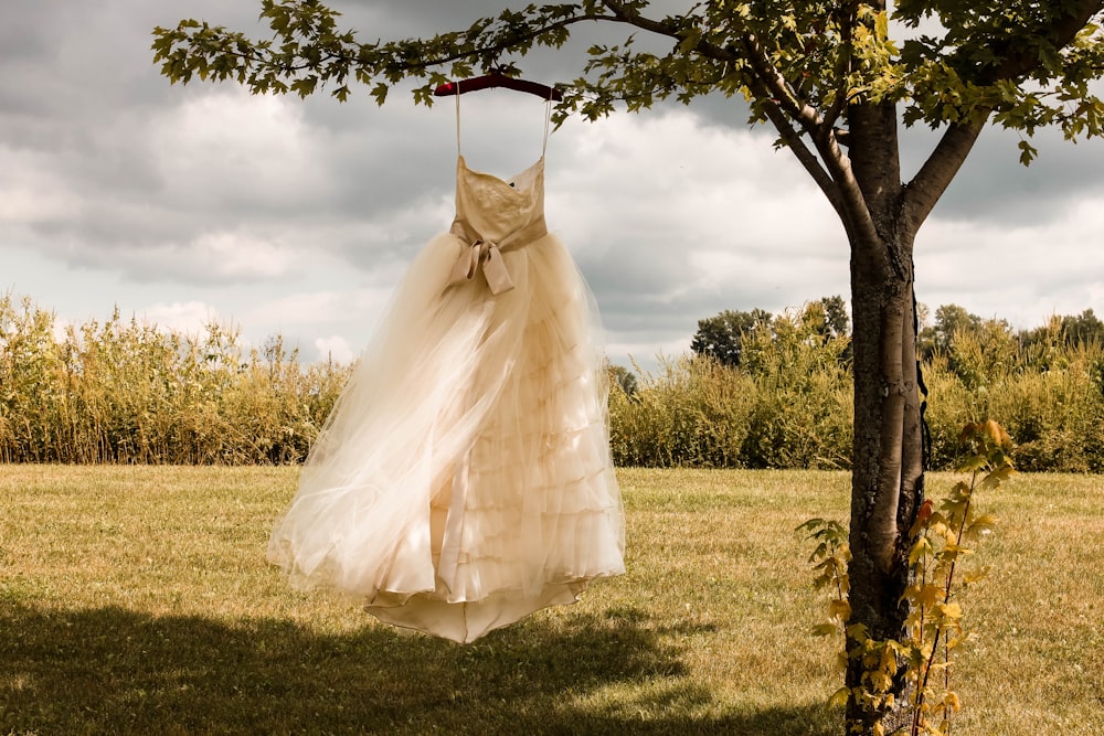vestido de noiva branco pendurado na árvore verde