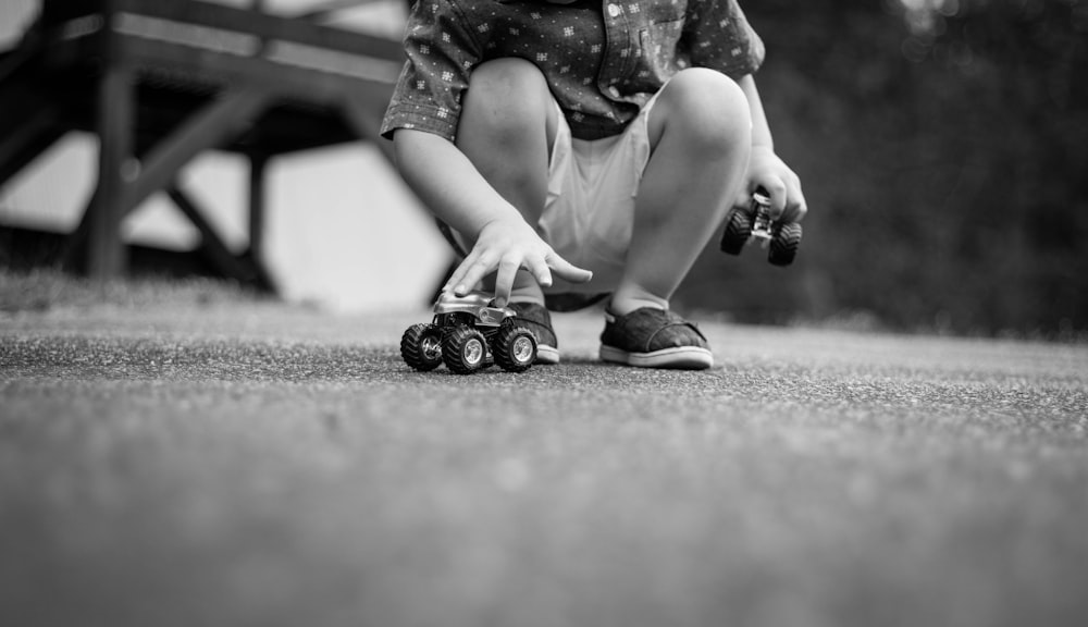 grayscale photography of girl playing car toys