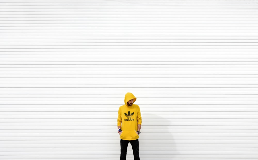 minimalist photography of man standing against white wall