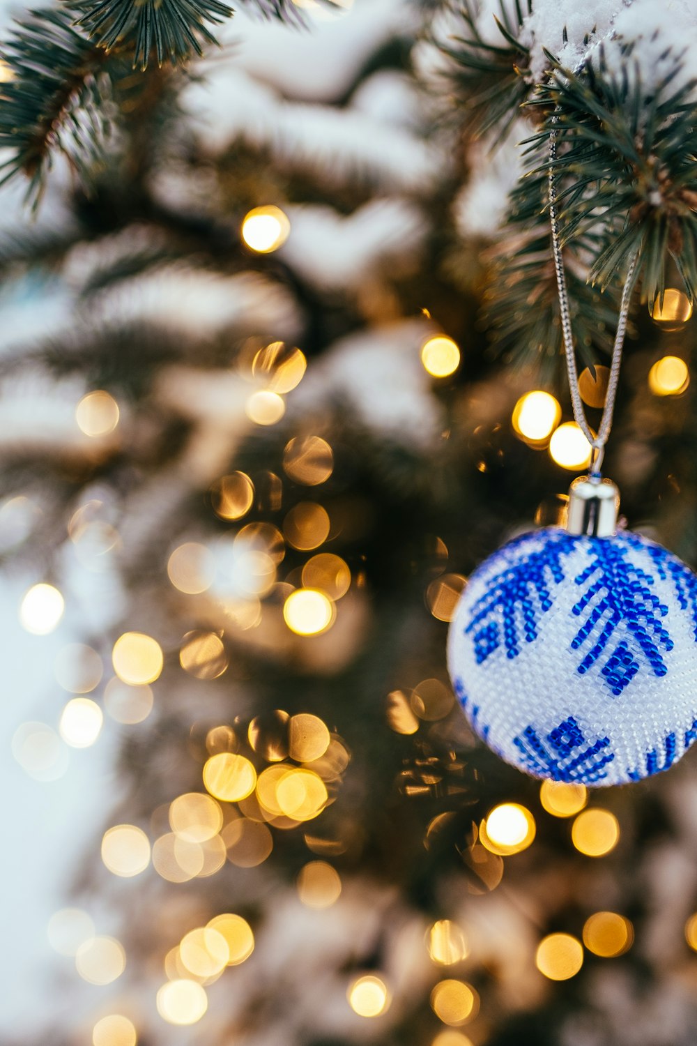 blue and white bauble hanging on christmas tree in bokeh photography