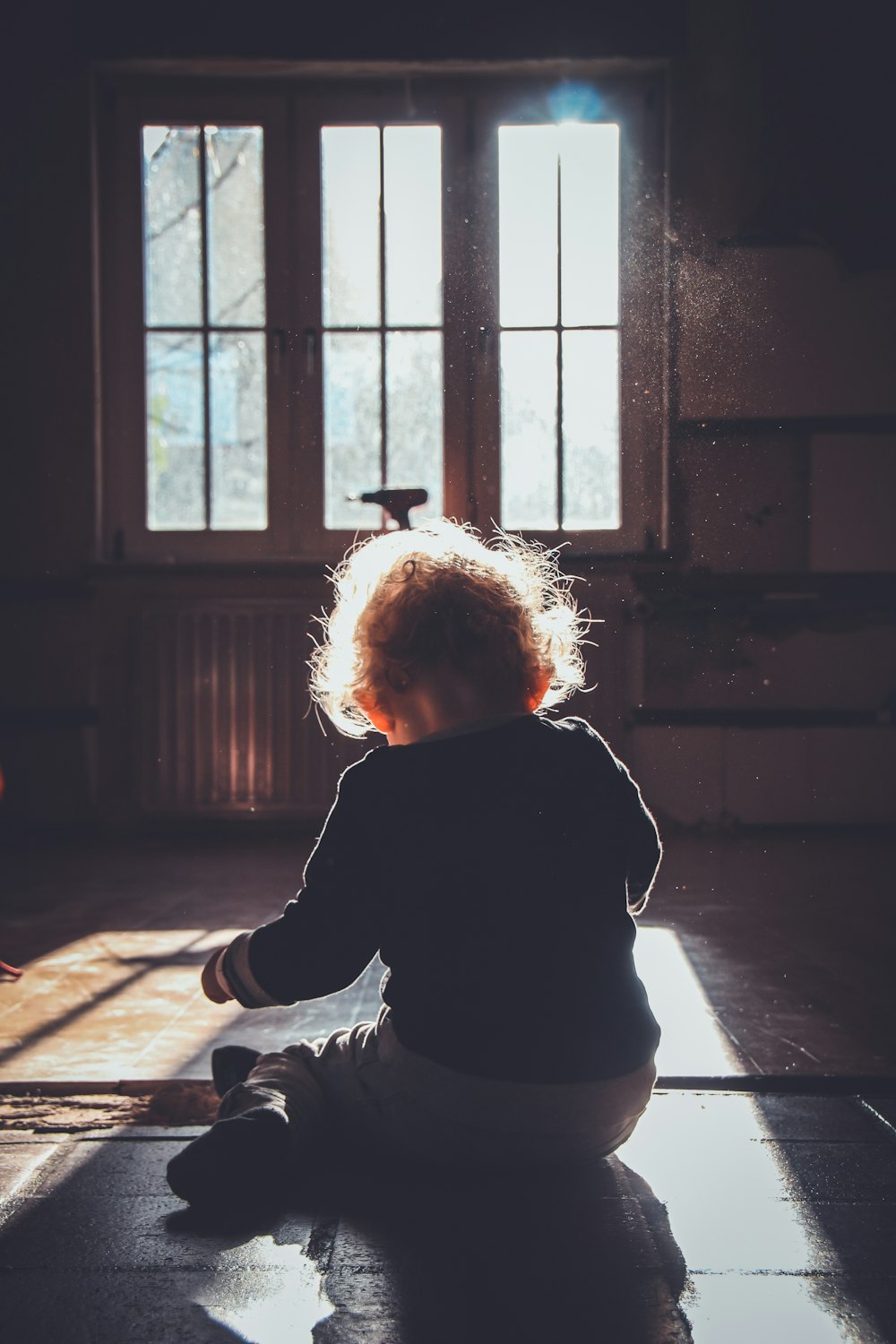 niño pequeño sentado en el piso de madera marrón