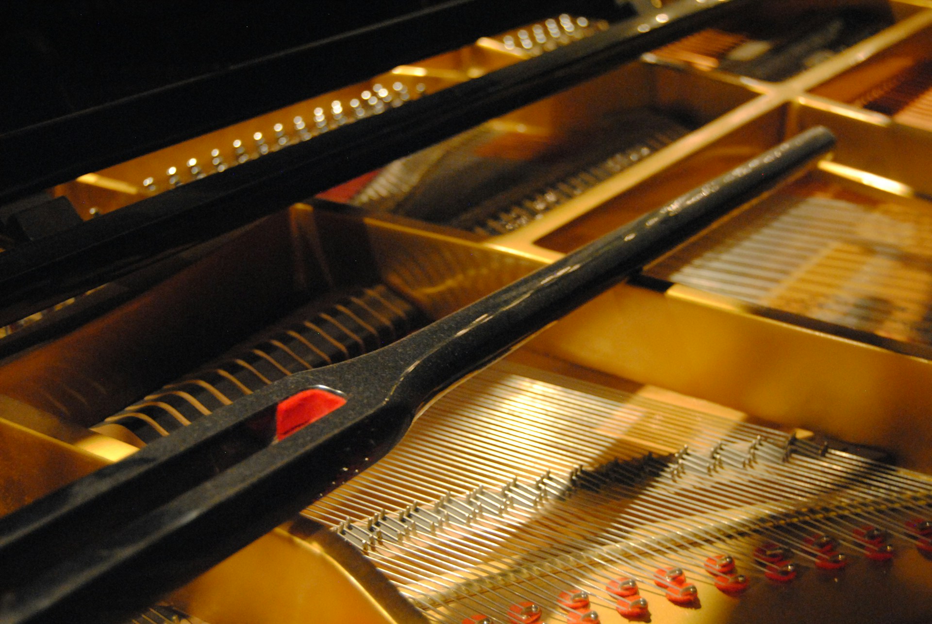 A close-up of a grand piano's strings and hammers, bathed in warm, golden light, evoking the depth of orchestral sound.