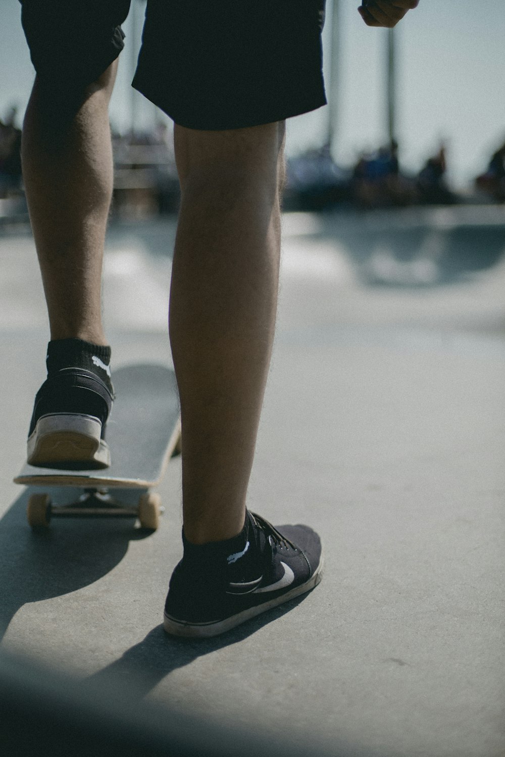 person wearing black-and-white Nike sneakers and black skateboard