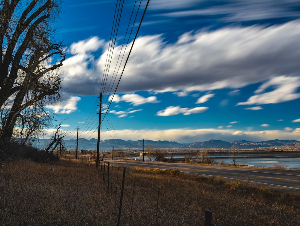 empty gray road under blue and white sky