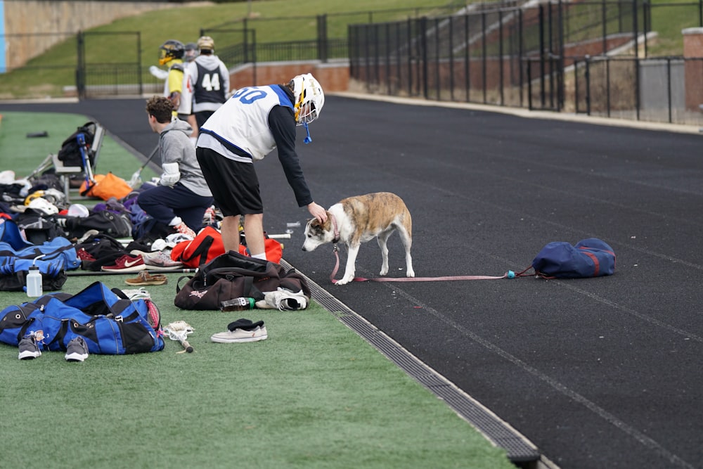 man patting dog while in sports field