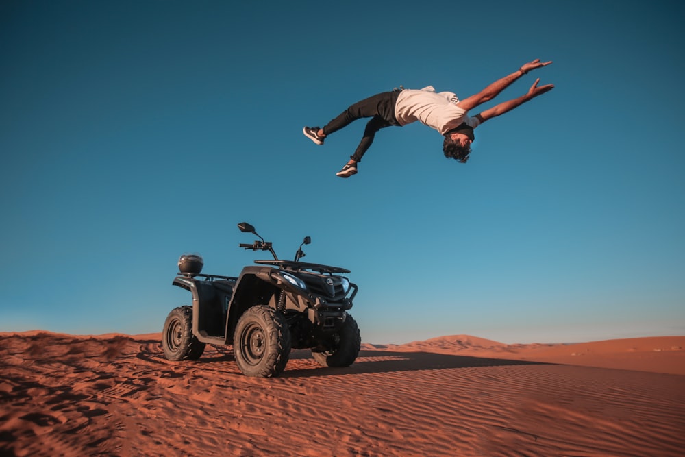 man backflipping on gray sand