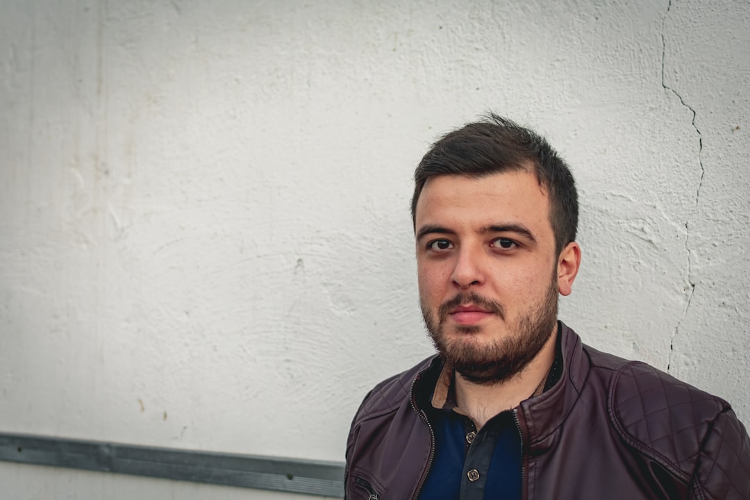 bearded man standing near white concrete wall