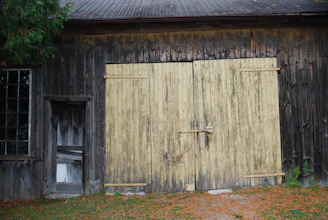 Rustic wooden barn doors with peeling paint standing against a twilight sky