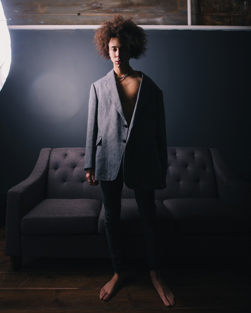 man standing wearing black blazer behind sofa