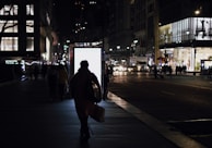 Evening cityscape with a person carrying an urbanray tote bag, lights twinkling in the background.