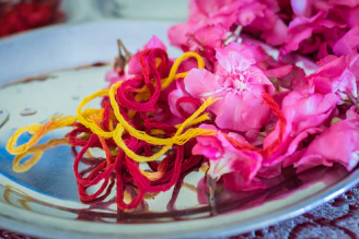 purple-petaled flowers beside pink and yellow threads