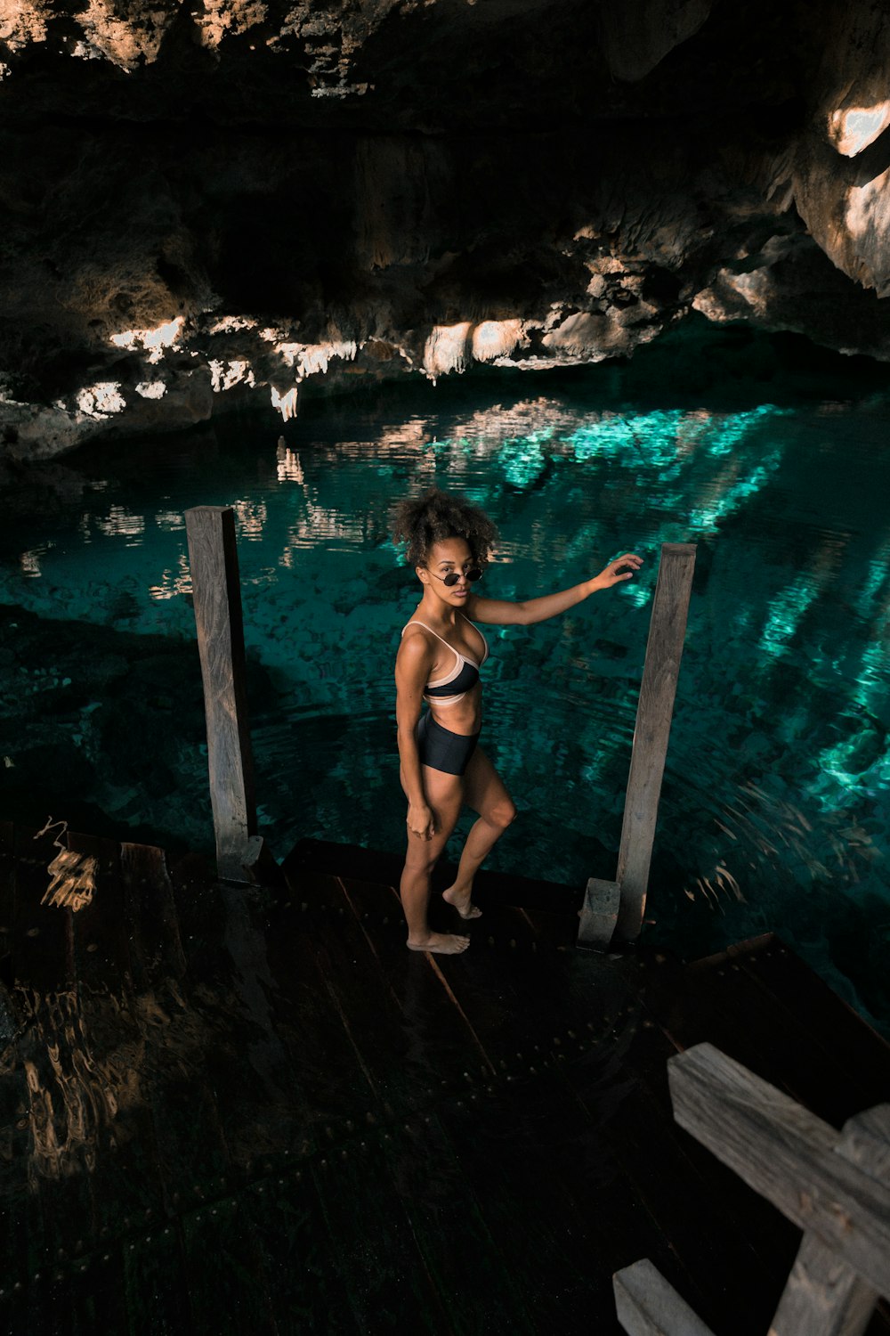 woman standing on wooden dock inside cave
