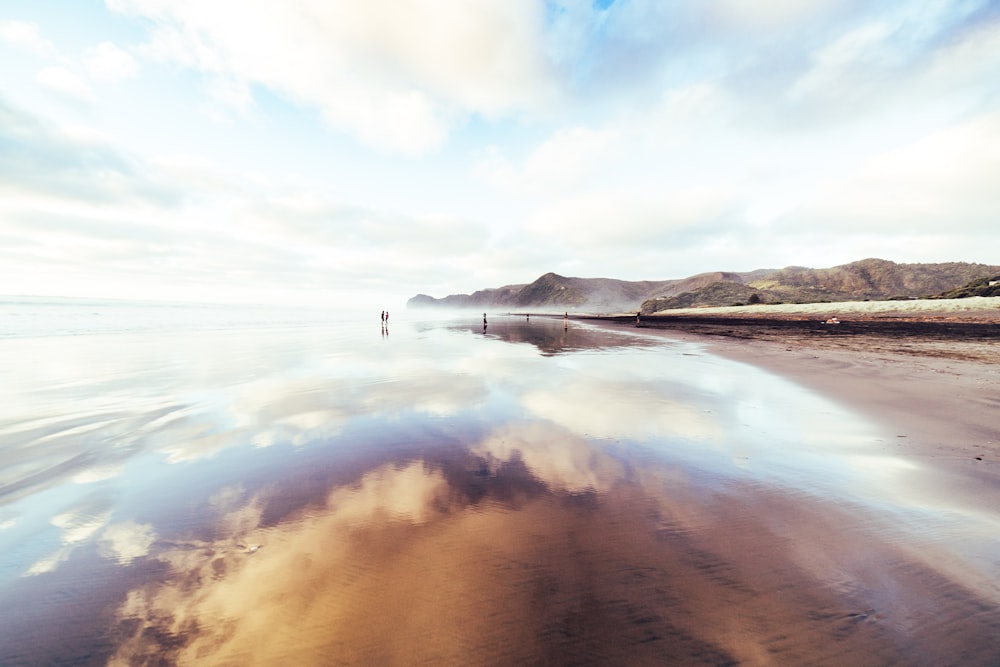 white cloudy sky reflection on clear sea water by the beach