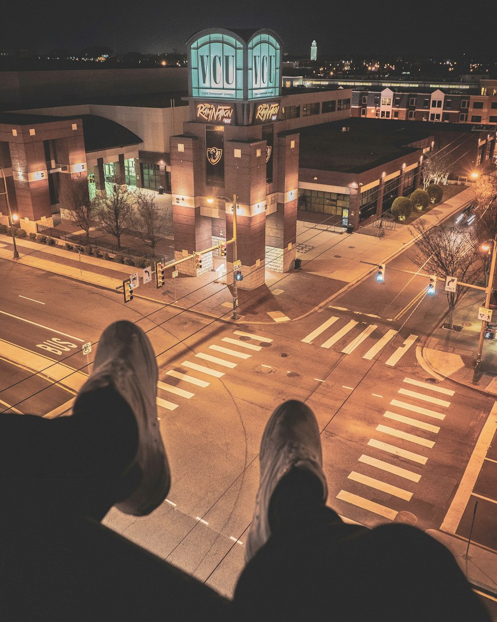 조명이 켜진 거리를 내려다 보는 건물 꼭대기에 앉아있는 사람
