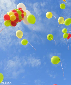 A playful scene of bouncing rubber balls caught mid-air against a bright blue sky.