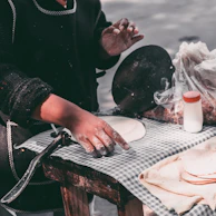 Artisan hands gently shaping fresh aish baladi flatbreads dusted with turmeric on a rustic wooden table.