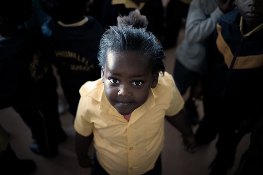boy in yellow dress shirt surrounded by people