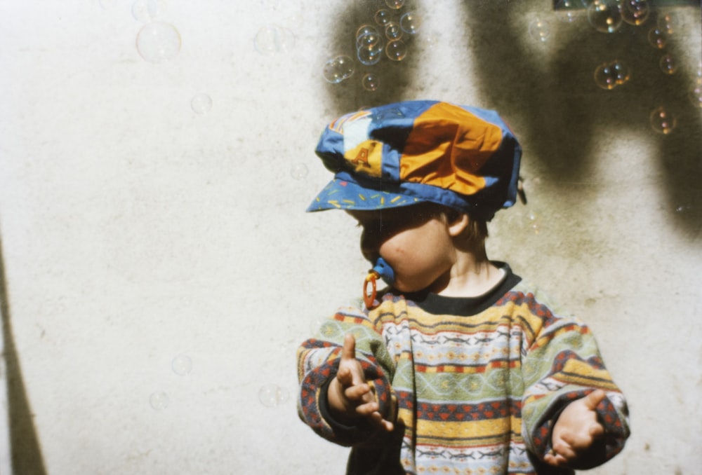 child in multicolored top sucking a pacifier