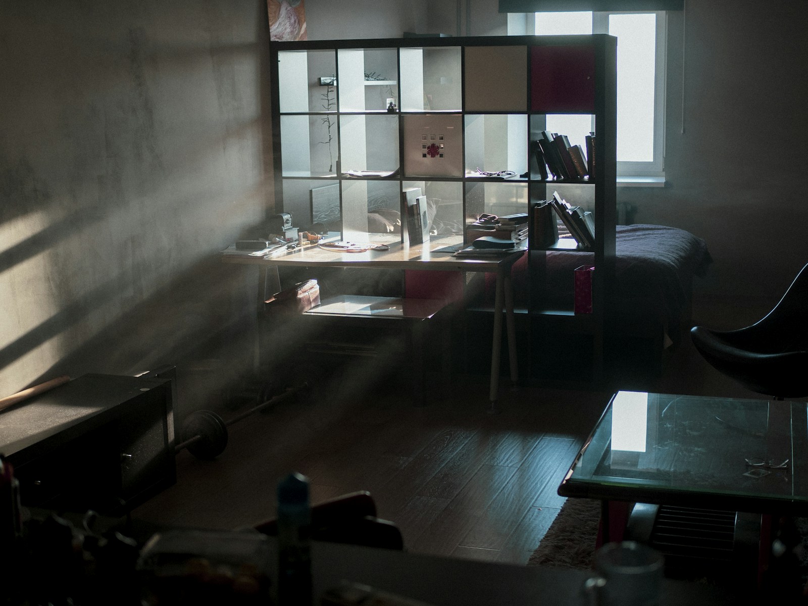 warm dim studio apartment with desk against shelves and moody lighting