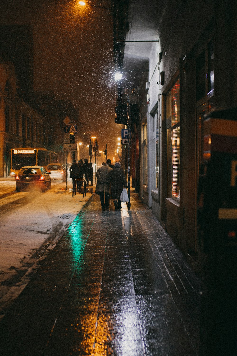 two person walking on sidewalk at night-time