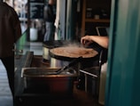 A tapioca being prepared on a hot griddle with steam rising, showcasing the cooking process.