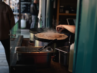 A tapioca being prepared on a hot griddle with steam rising, showcasing the cooking process.