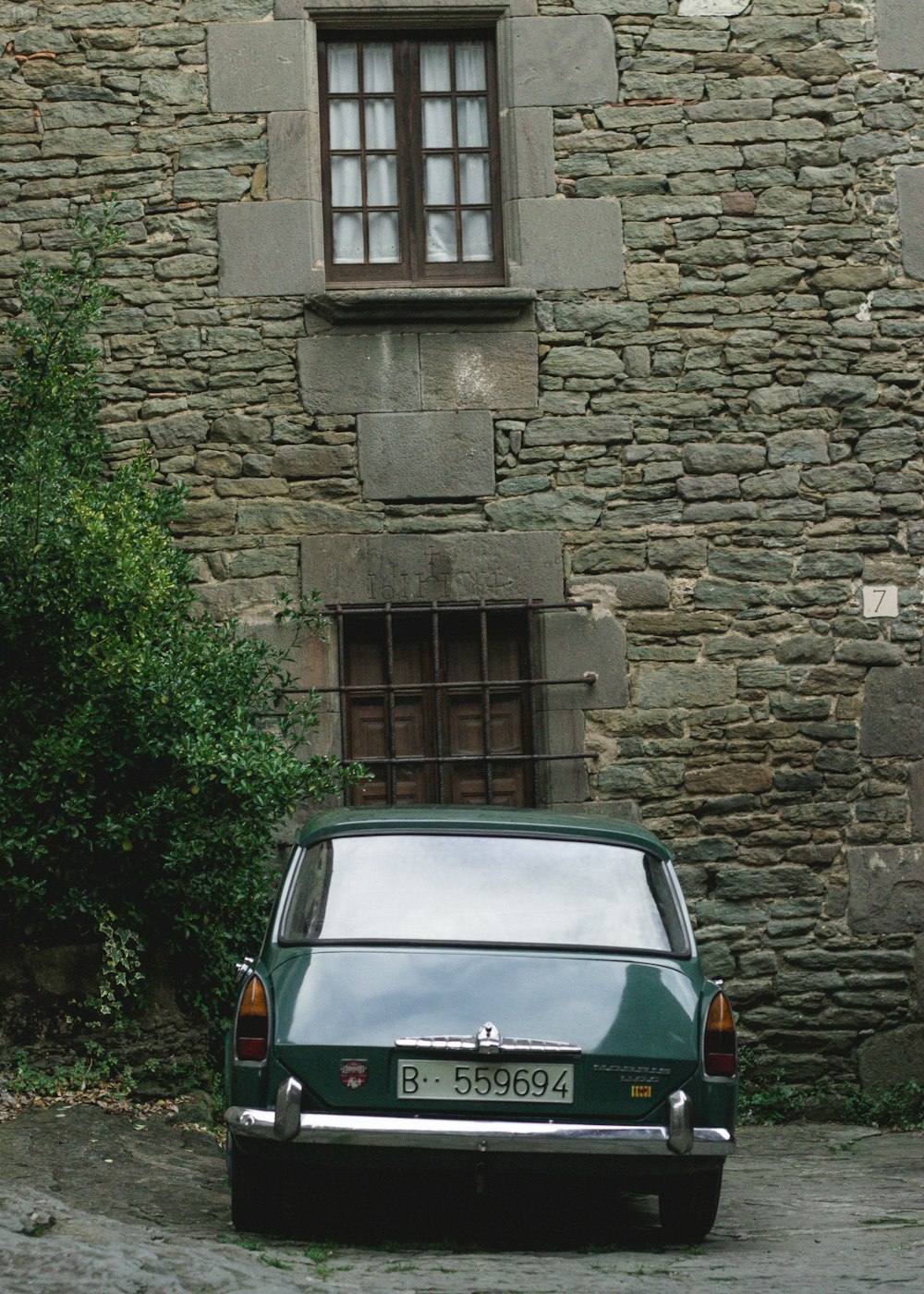green car parked near gray concrete house