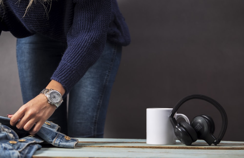 black JBL wireless headphones beside white ceramic mug