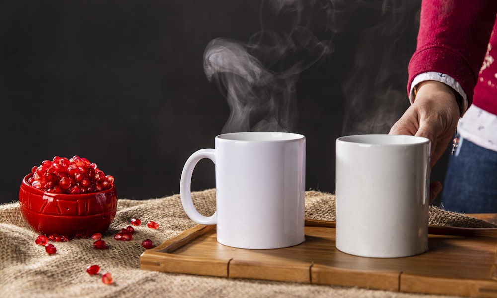 two white ceramic mugs on brown wooden tray