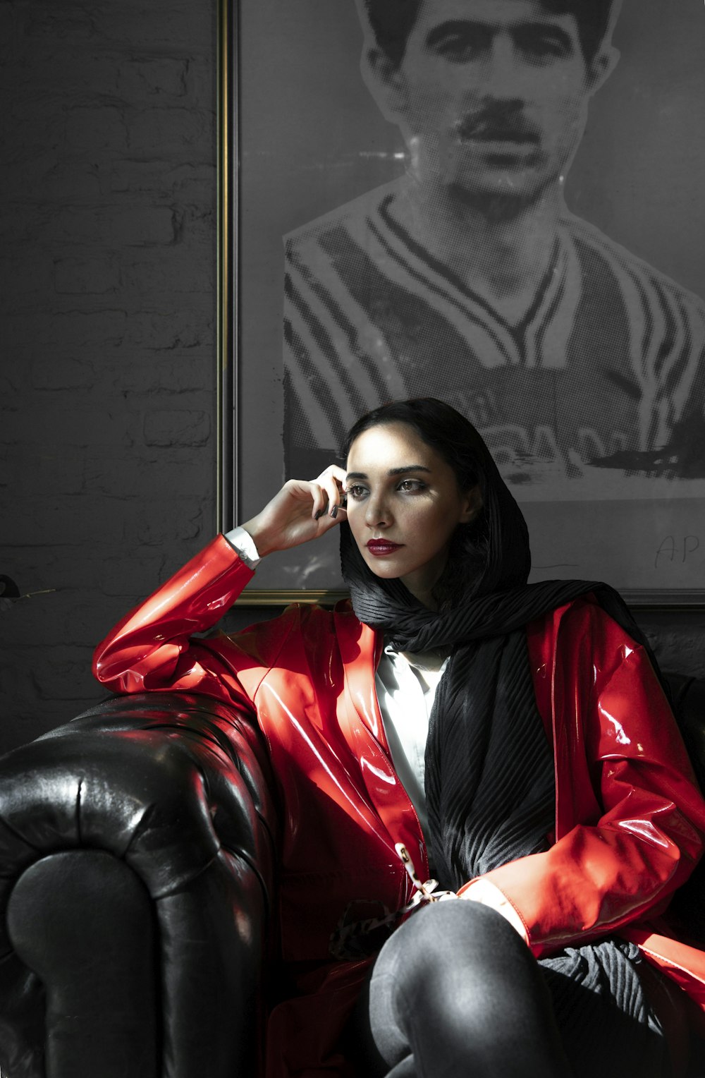 woman sitting on black sofa behind portriat on wall