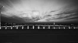 A black and white photograph capturing a serene urban landscape at dusk.