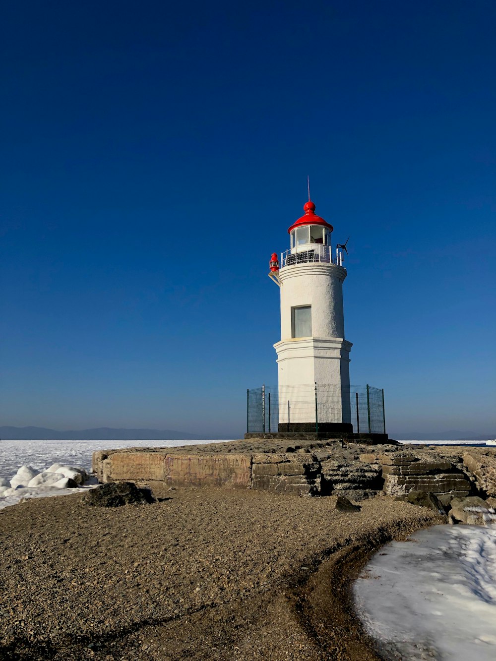 Weißer und roter Leuchtturm tagsüber unter blauem Himmel