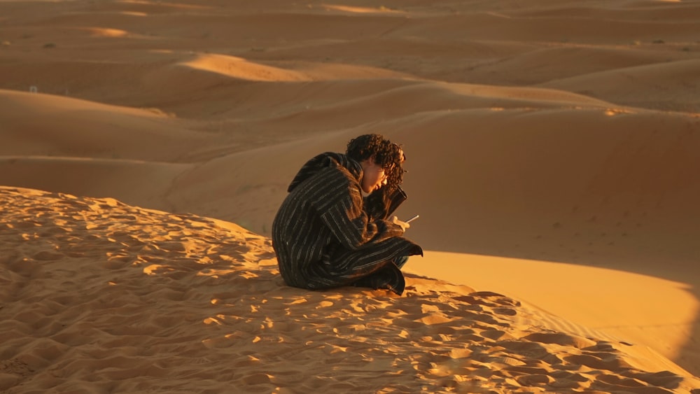 man sitting down on sand