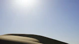 Wind-swept dunes with a Kalima surf bag resting on the sand under a clear blue sky.